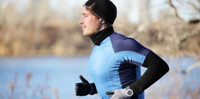 Runner man in fall running in autumn with gloves