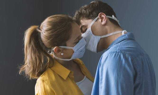 Young couple wearing a protective face mask and kissing